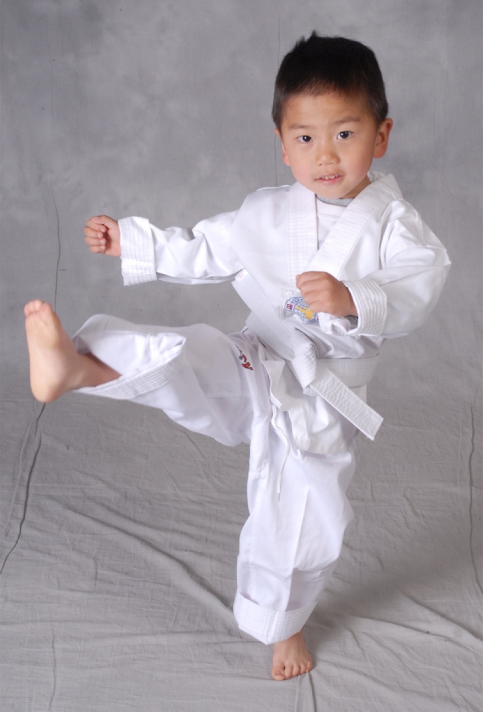 A young student in a white dobok practicing a front kick